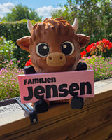 Welkomstbord met achternaam – Schotse hooglander houdt bord met Familien Jensen vast