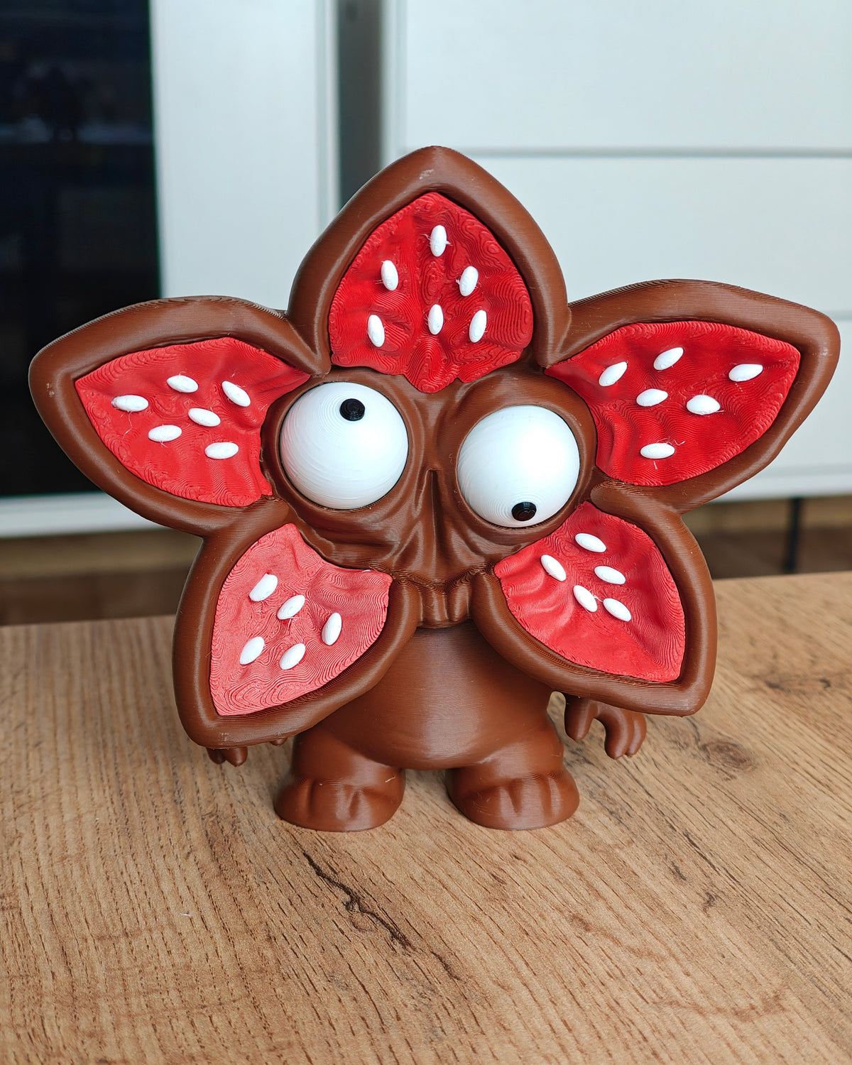 Monsterfiguur met bloemengezicht en grote beweegbare ogen, van voren gezien