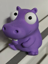 Gek nijlpaardfiguurtje met beweegbare ogen op bureau naast koffiekopje