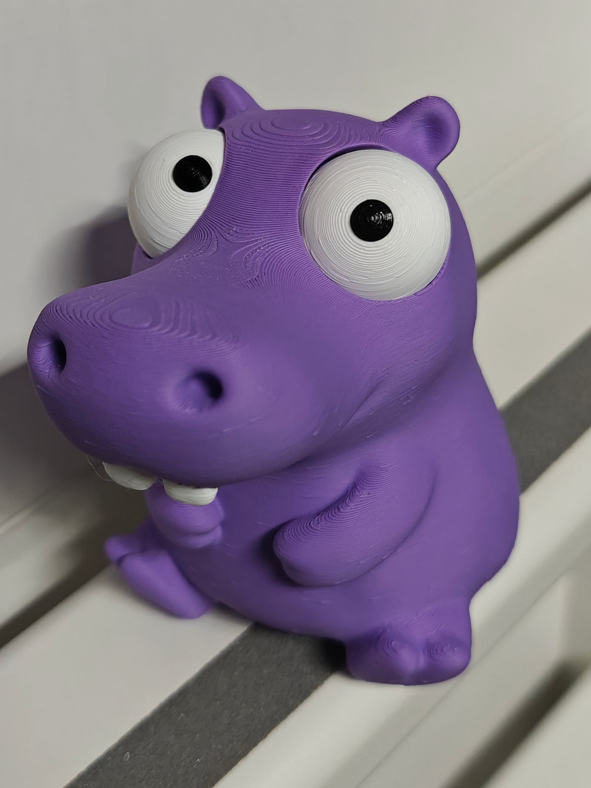 Gek nijlpaardfiguurtje met beweegbare ogen op bureau naast koffiekopje