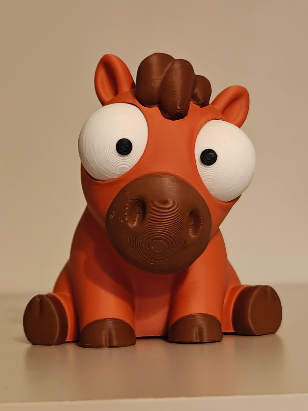 Close-up van een grappig paardenfiguurtje met grote beweegbare googly eyes op een wit vlak