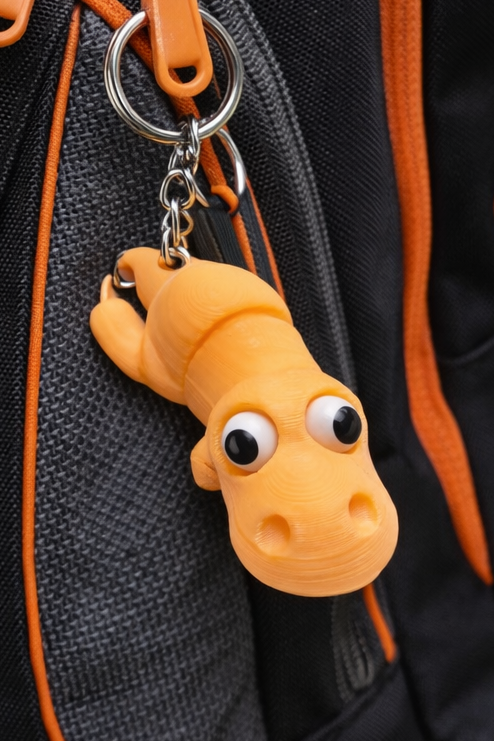 Oranje 3D-geprinte dinosaurussleutelhanger met googly eyes en metalen ring