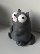 Gek kattenfiguurtje met beweegbare ogen op bureau naast koffiemok