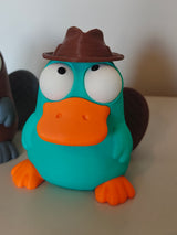 Vogelbekdierfiguurtje met wiebeloogjes op een houten bureau naast een koffiekop