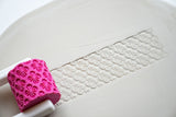 Textuurroller met handvat voor keramiek op een wit oppervlak met patroondetail