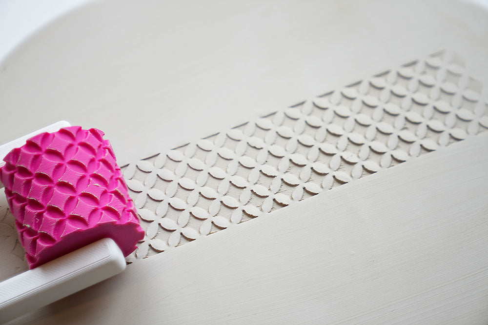 Textuurroller met handvat voor keramiek op een wit oppervlak met patroondetail