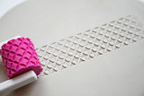 Textuurroller met handvat voor keramiek op een wit oppervlak met patroondetail