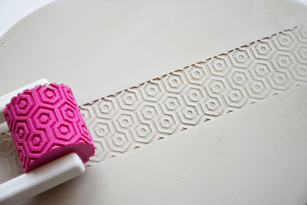 Textuurroller met handvat voor keramiek op een wit oppervlak met patroondetail