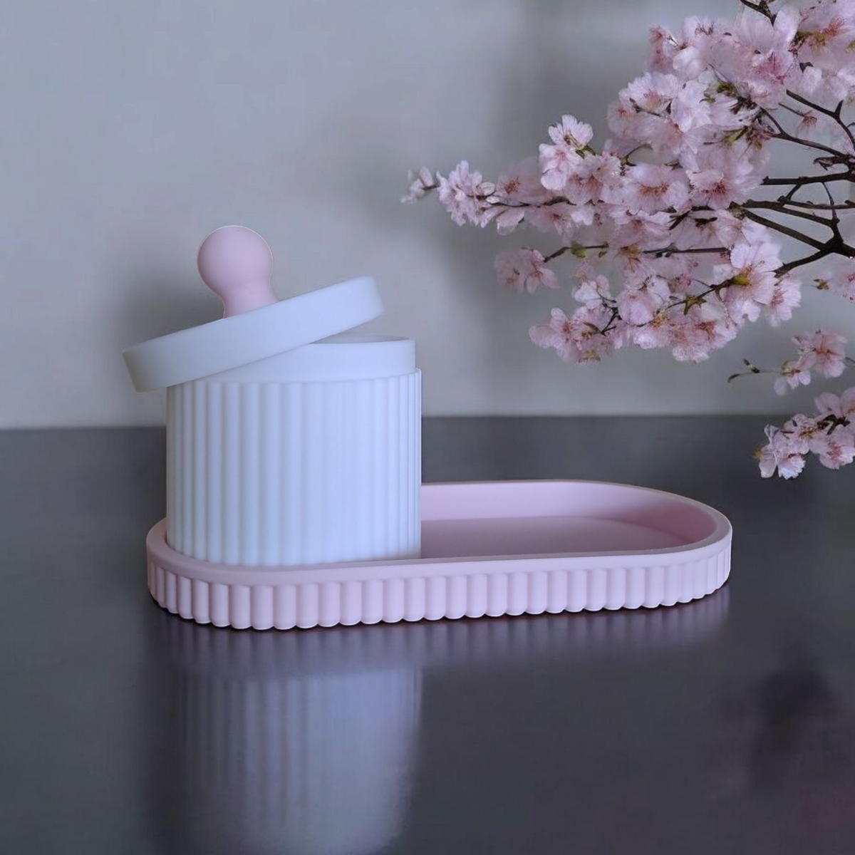 Close-up van een geribbeld sieradenpotje met deksel en bijpassend bakje in roze en wit