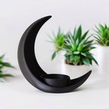 Halvemaanbloempot op een houten plank met een klein vetplantje in een minimalistische ruimte