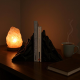 Paar boekensteunen in bergvorm die boeken rechtop houden op een houten plank