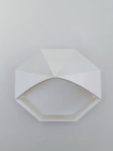 Close-up van een geometrisch piramidebakje met gefacetteerde hoeken en achthoekige bodem