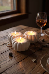 Pompoen-theelichthouder voor de herfst met brandende kaarsjes op een houten plank