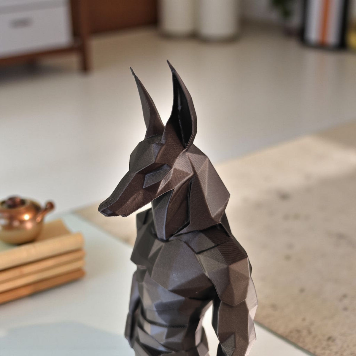 Low poly Anubis-beeld op een lichte plank met minimalistische decoratie