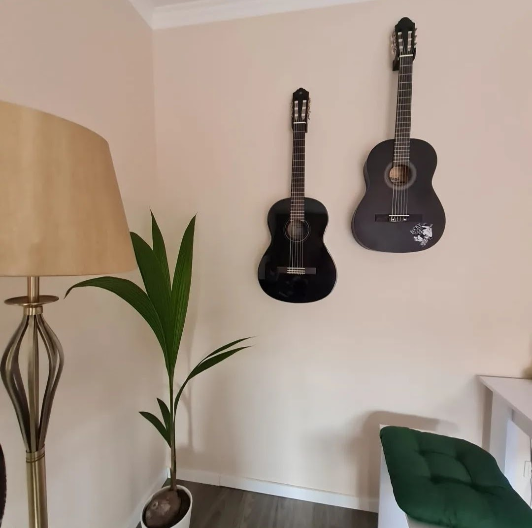 Elektrische gitaar aan witte wand in subtiele minimalistische houder