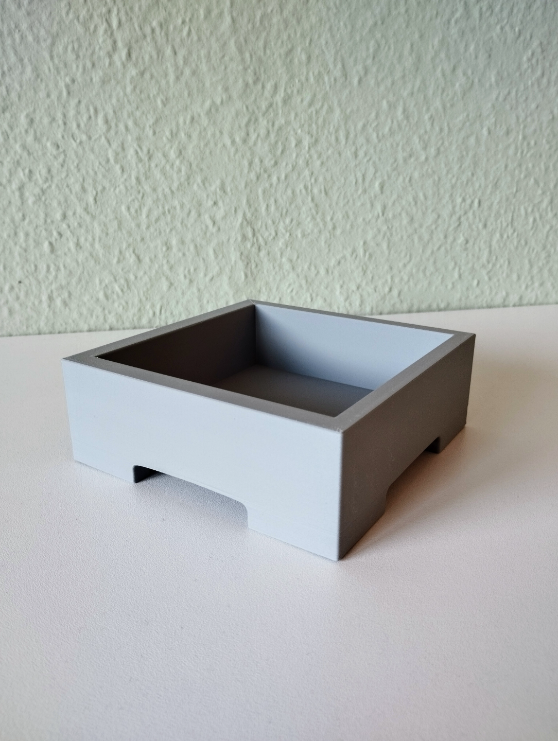 Minimalistische bonsaipot met een plantje op een lichte houten plank