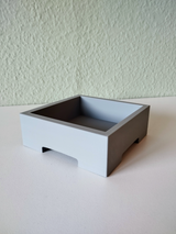 Minimalistische bonsaipot met een plantje op een lichte houten plank