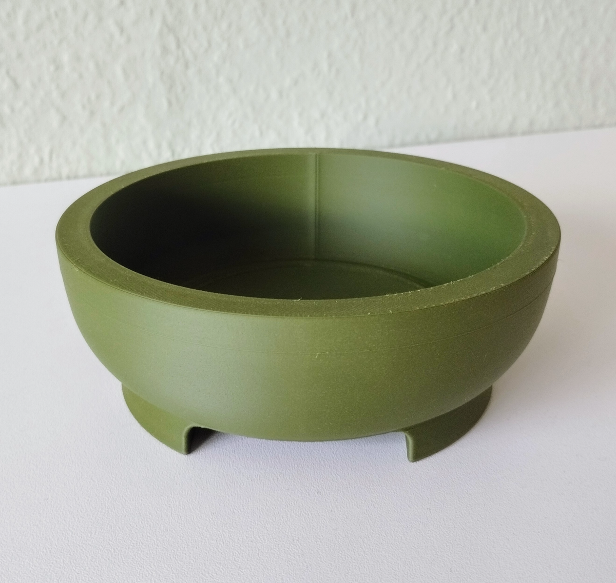 Close-up van een ronde bonsaipot met strakke geometrische vorm en geïntegreerde voet