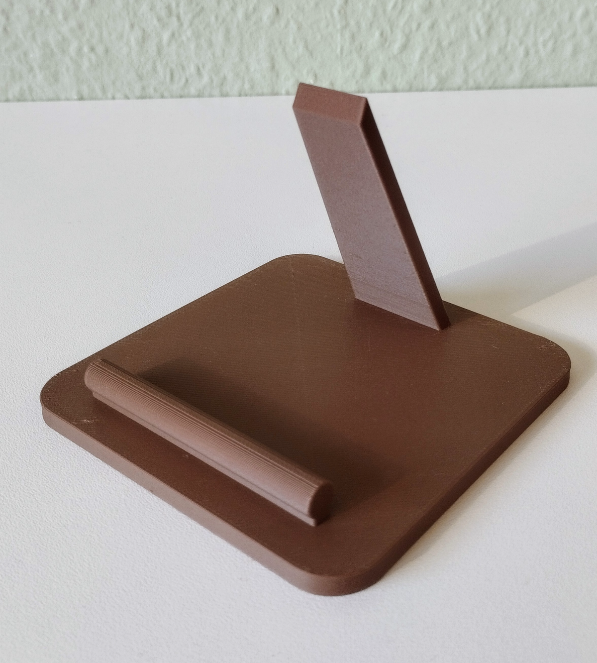Telefoonstandaard op een bureau bij een lamp en een notitieboek, met de telefoon in een goede kijkhoek