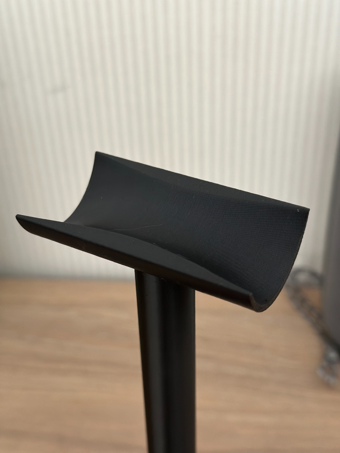 Minimalistische koptelefoonstandaard met strakke gebogen arm en compacte voet