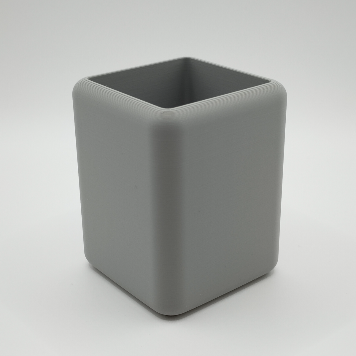 Minimalistische pennenhouder op een bureau met schrijfgerei en een notitieboekje
