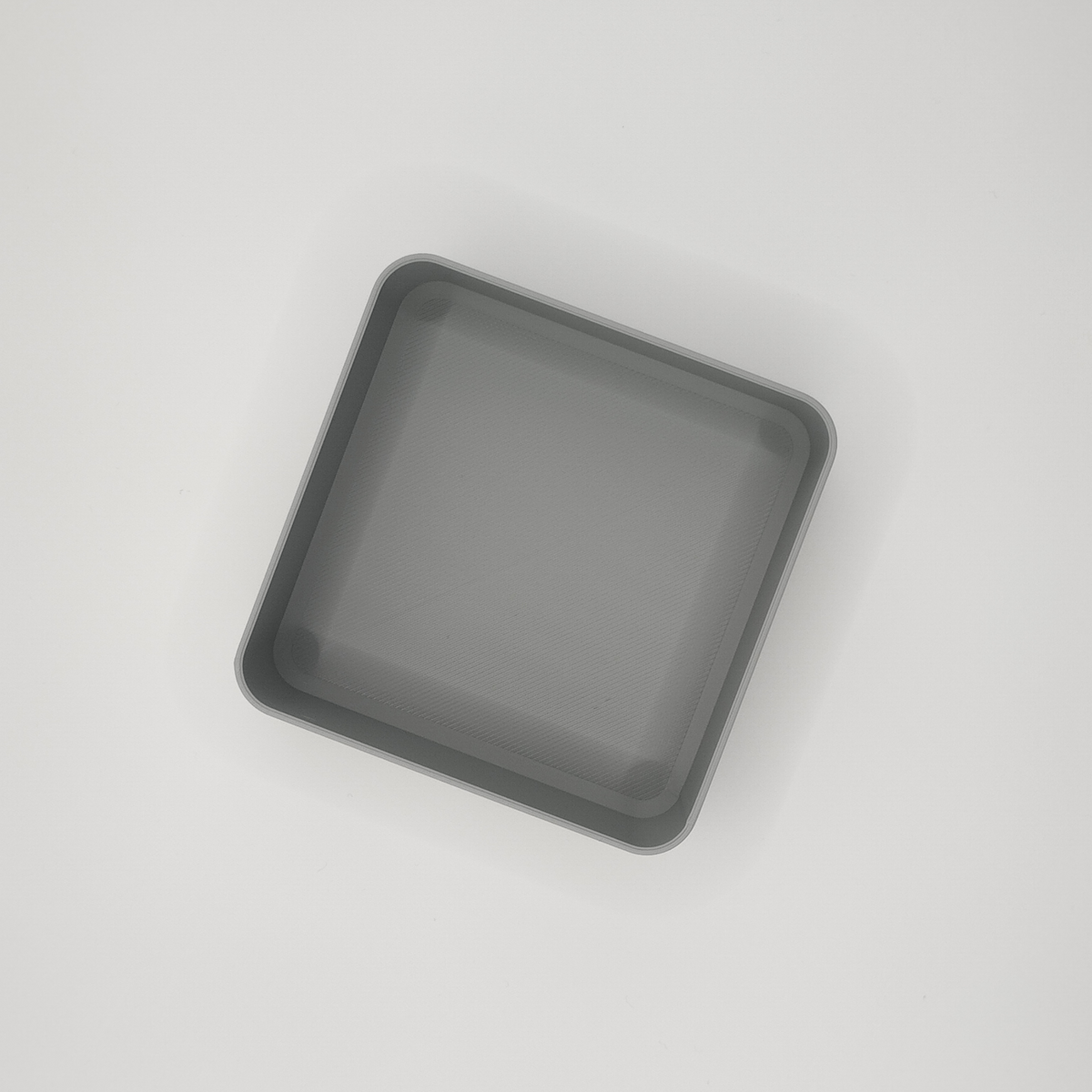 Detail van het lage binnenvlak van een minimalistisch vierkant schaaltje voor kleine spullen