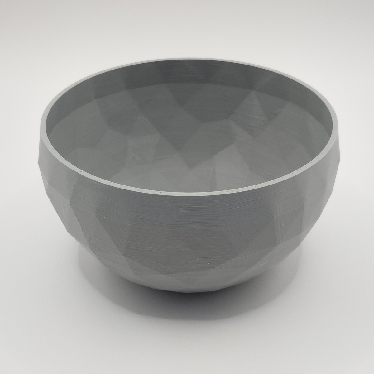Low poly designschaal op een minimalistische plank met neutrale decoratie