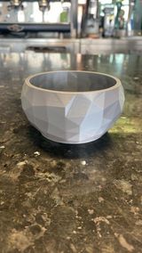 Detail van hoekige facetten op een minimalistische diamantschaal die het licht vangen