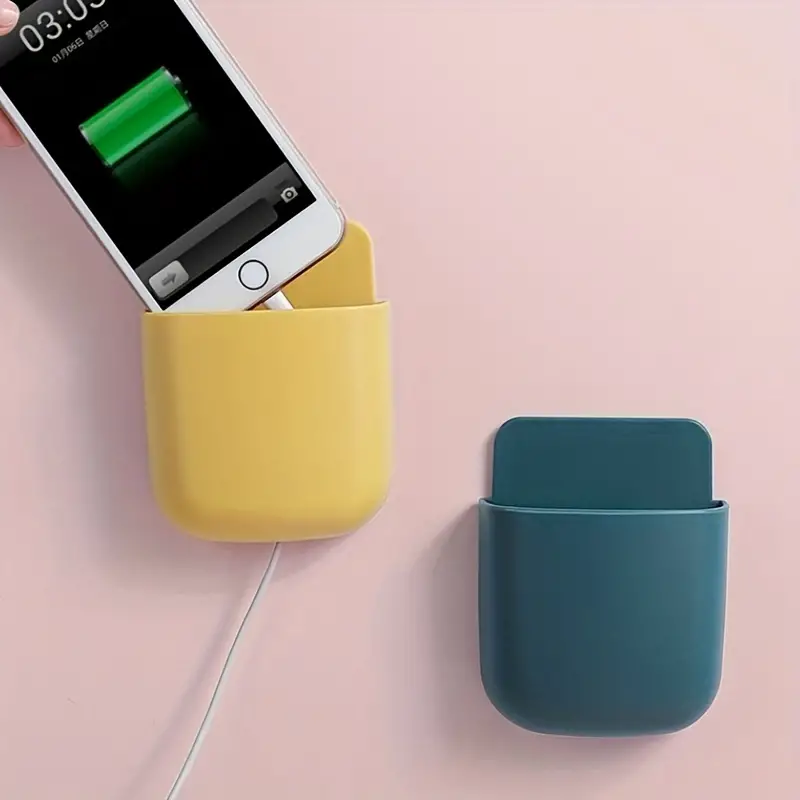 Telefoonhouder aan de muur boven een bureau met smartphone en afstandsbediening