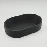 Ovaal bakje op een haltafel met sleutels en munten en minimalistische woondecoratie