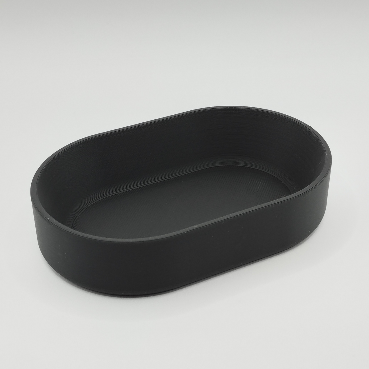 Ovaal bakje op een haltafel met sleutels en munten en minimalistische woondecoratie