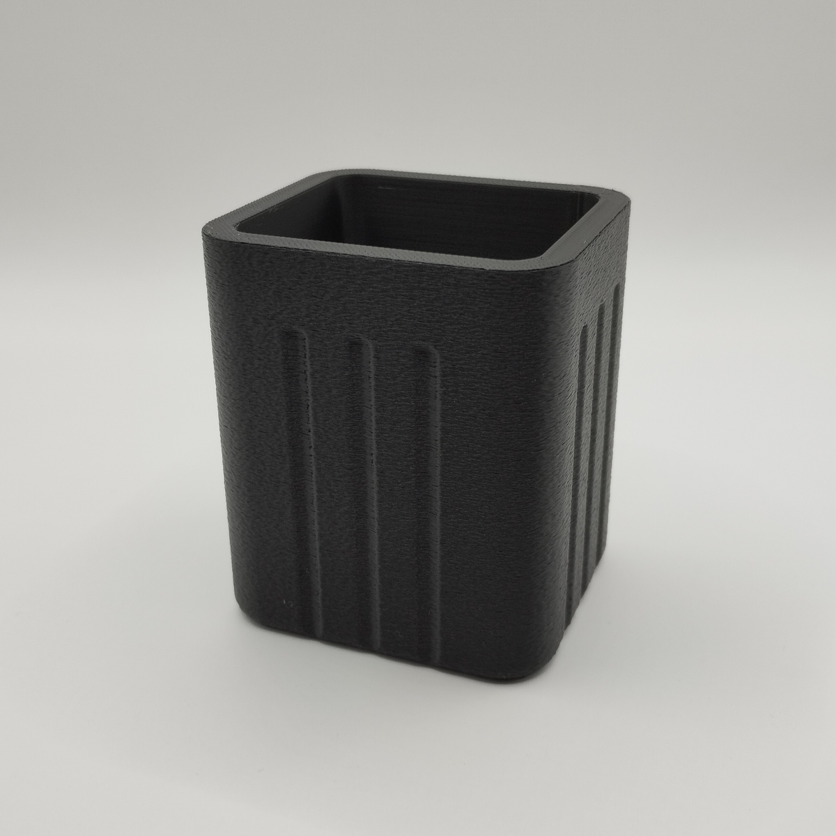 Minimalistische pennenhouder op een houten bureau met balpennen en een notitieboekje