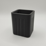 Minimalistische pennenhouder op een houten bureau met balpennen en een notitieboekje