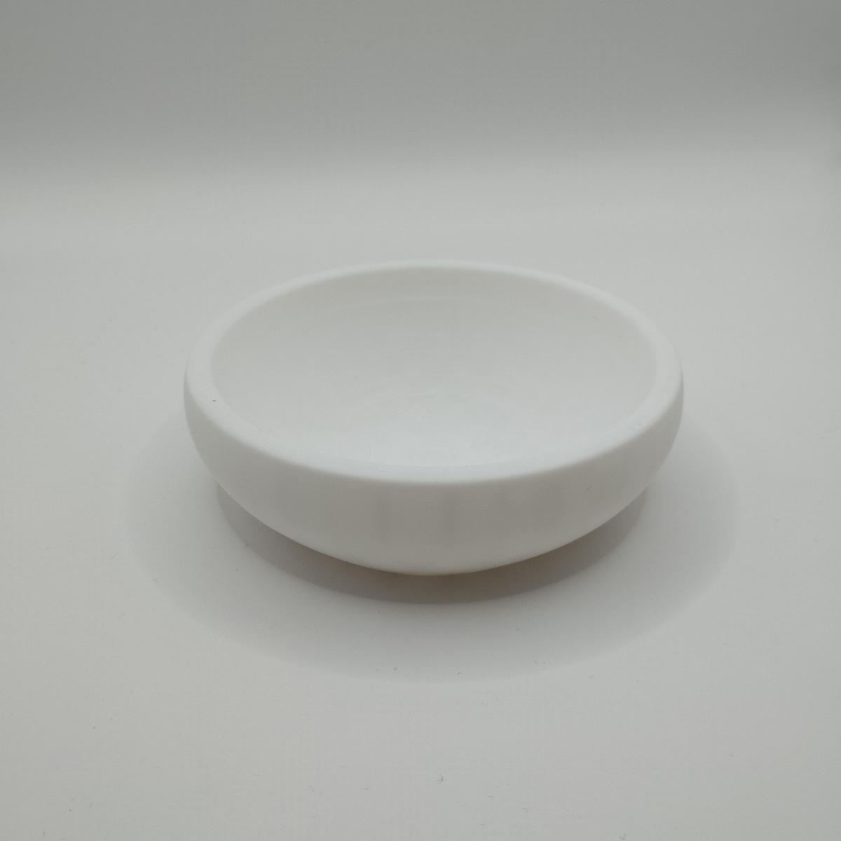 Minimalistische schaal voor sleutels en munten op een haltafel met verspreid liggende sleutels