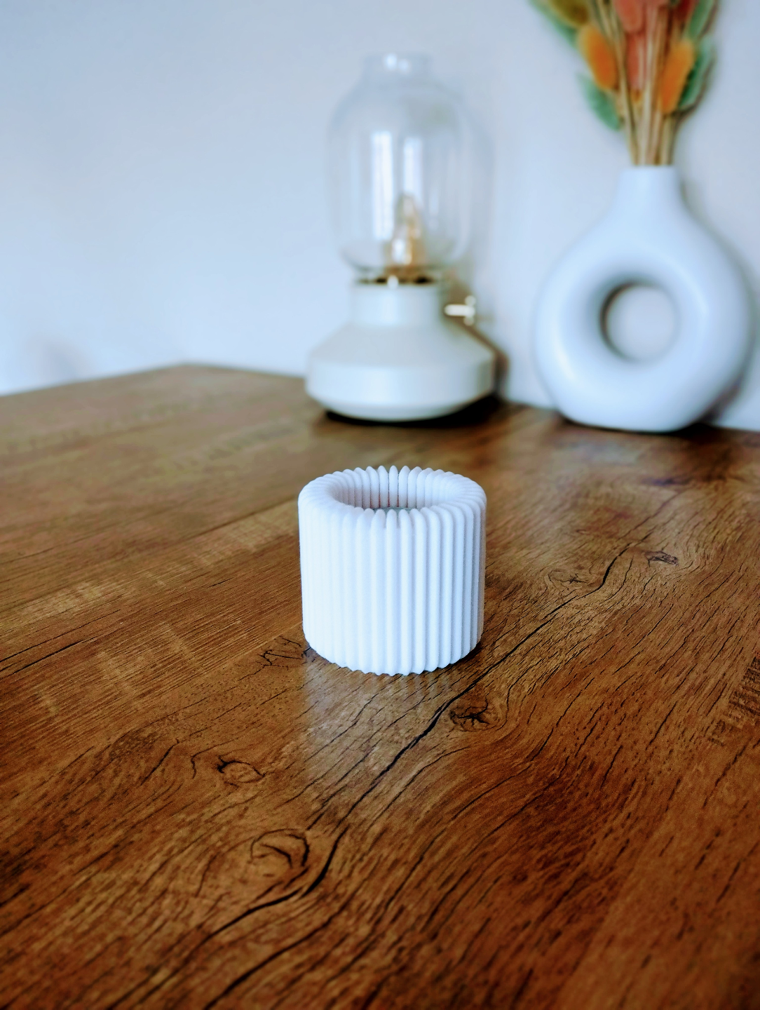 Geribbelde theelichthouder met brandend ledlampje op een witte plank
