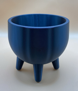 Plantenpot in mid-centurystijl met pootjes en een kleine vetplant op een houten plank