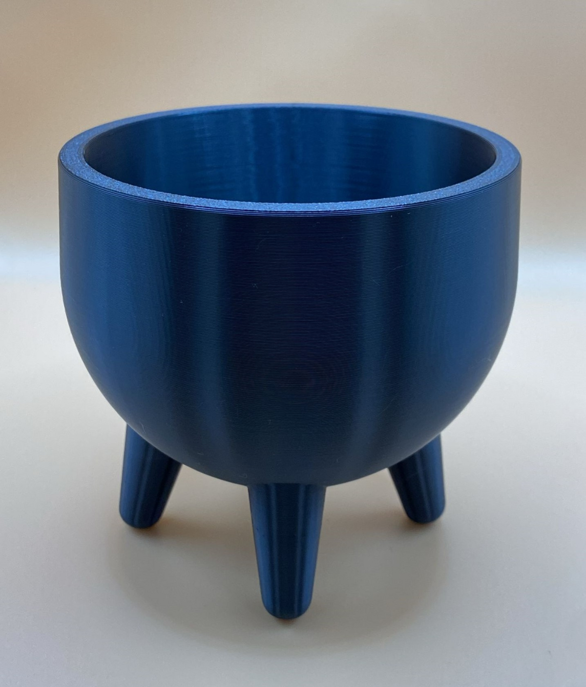 Plantenpot in mid-centurystijl met pootjes en een kleine vetplant op een houten plank
