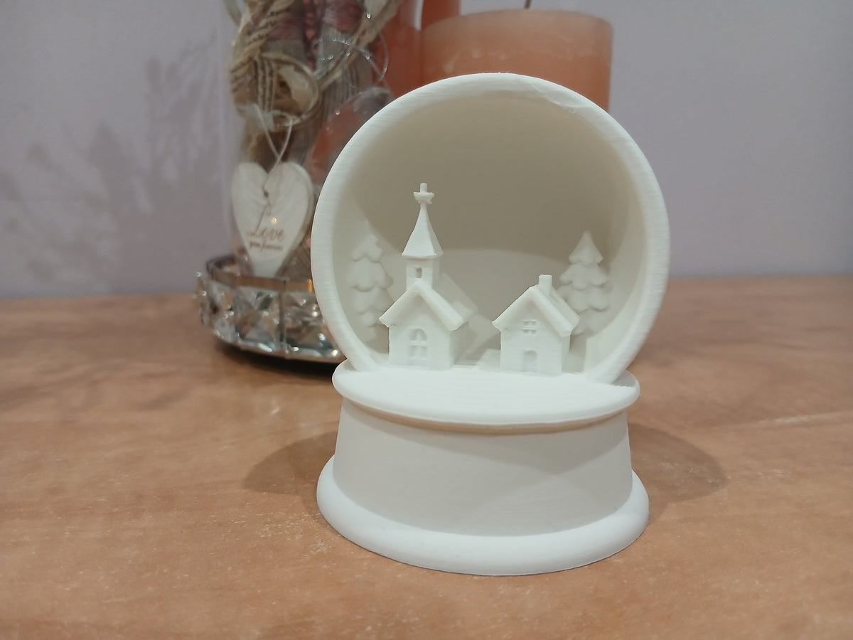Kerstdorp met kerk, huis en sparren in sneeuwbollijst