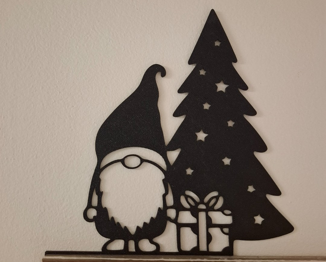 Kabouterfiguurtje met cadeautje bij de kerstboom