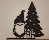 Kabouterfiguurtje met cadeautje bij de kerstboom