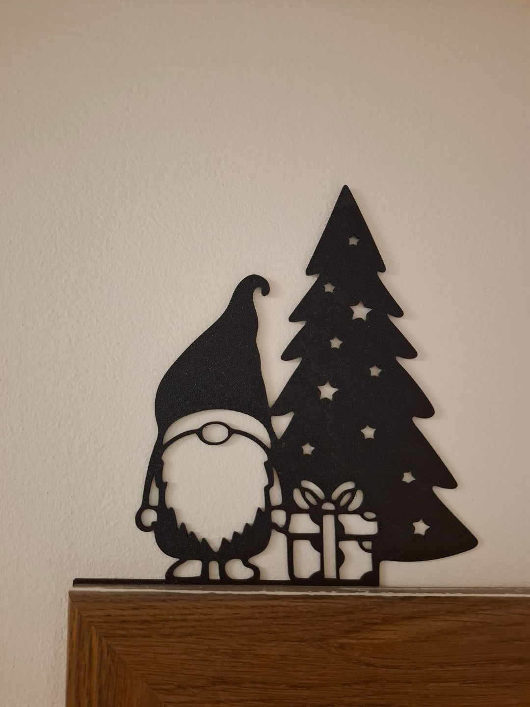 Kabouterfiguurtje met cadeautje bij de kerstboom