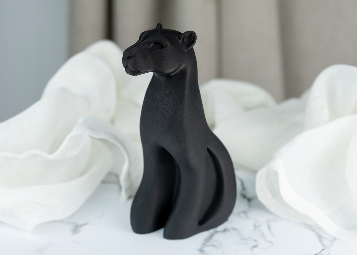 Detail van panter-sculptuur met vloeiend silhouet in mat zwart