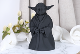 Yoda-beeld op een houten bureau bij een plantje en een stapel boeken