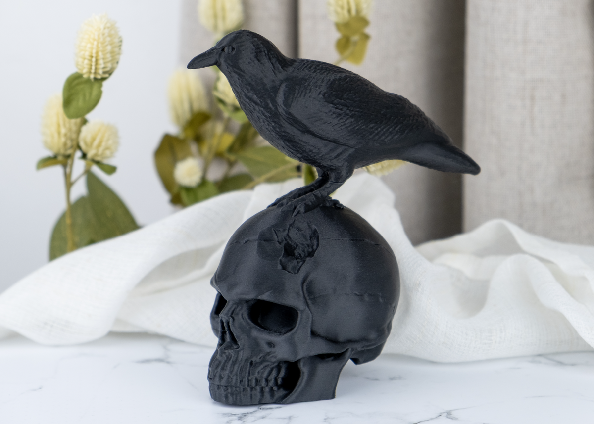 Sculptuur van een ravenschedel op een donkere houten plank met kaarsen en gedroogde planten