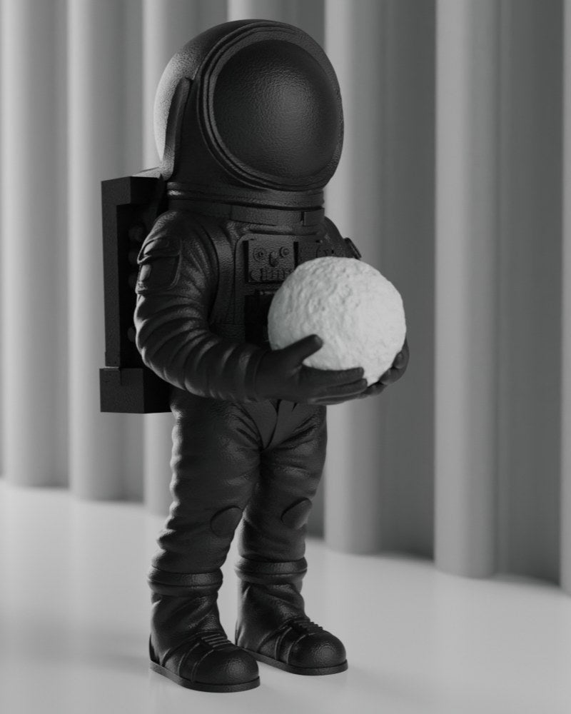 Mat zwarte astronautensculptuur op een wit bureau – ruimtedecoratie, vooraanzicht