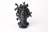 Medusa-buste op een donkere houten plank in een minimalistisch interieur
