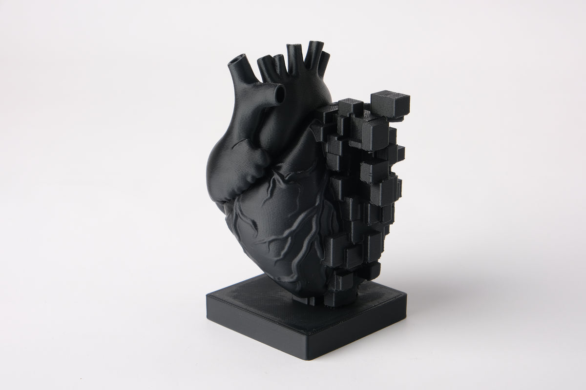 Pixelhartsculptuur op een houten bureau naast boeken en een plantje