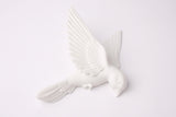 Minimalistische witte wandsculptuur met vogels op een warmgrijze woonkamermuur