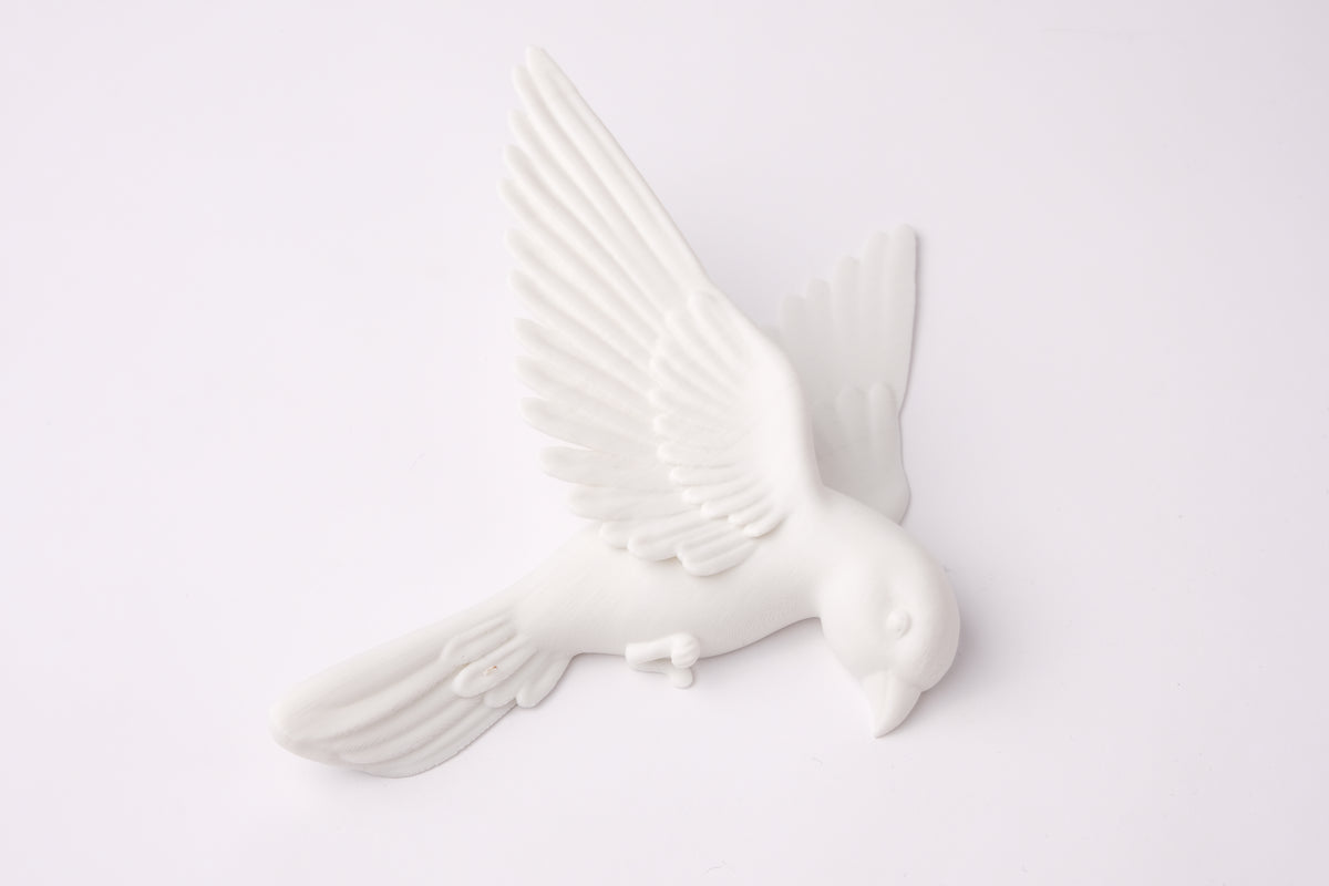 Minimalistische witte wandsculptuur met vogels op een warmgrijze woonkamermuur