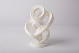 Minimalistische abstracte oneindigheidssculptuur op een lichte houten plank met neutrale decoratie